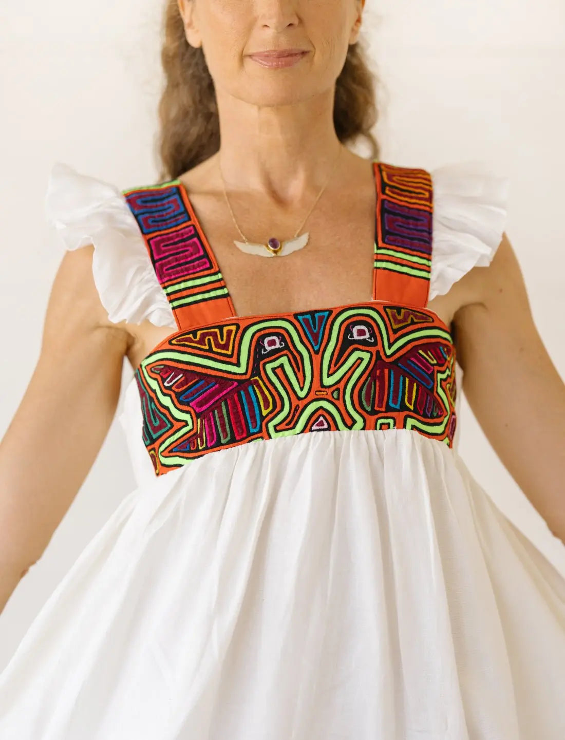 A close-up of the mola embroidery handmade by the Kuna People of Panama. This Indigenous craft is made from a meticulous process of layering and cutting fabric to reveal bold designs such as these two pelicans. Many of their embroideries are nature-inspired due to the Kuna People's rich connection to nature. We ethically source these molas directly from master Kuna artisans in Panama and Colombia, supporting Indigenous women and helping preserve their traditions for generations to come. 