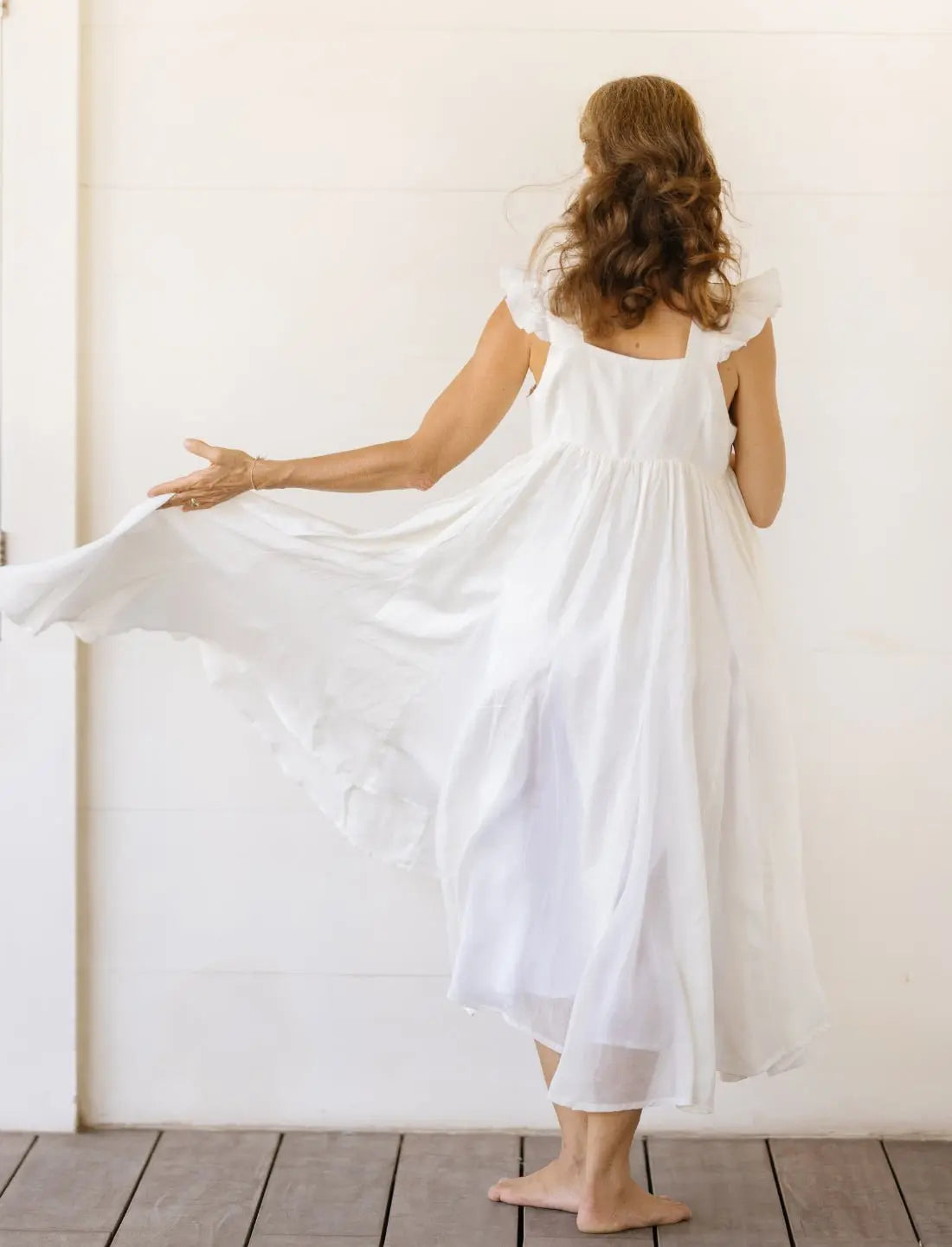 The back of the Yemaya Embroidery Gown is solid white linen. The flutter sleeve include delicate ruffles that look feminine and sweet. The gown is flowy, comfortable and airy so it's easy to slip on and look instantly elegant.